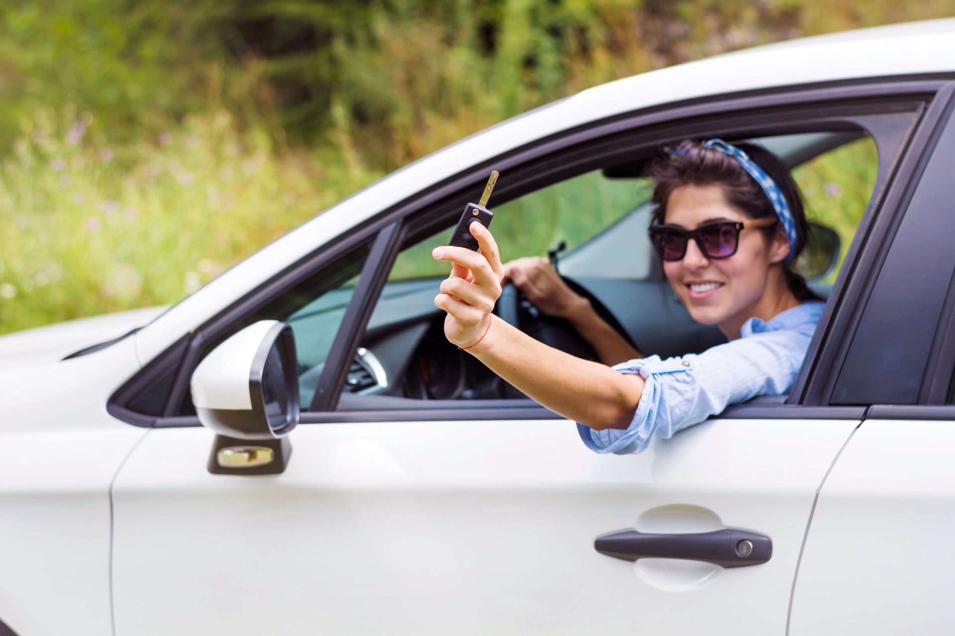 Happy woman in a car holds a car key in her hand